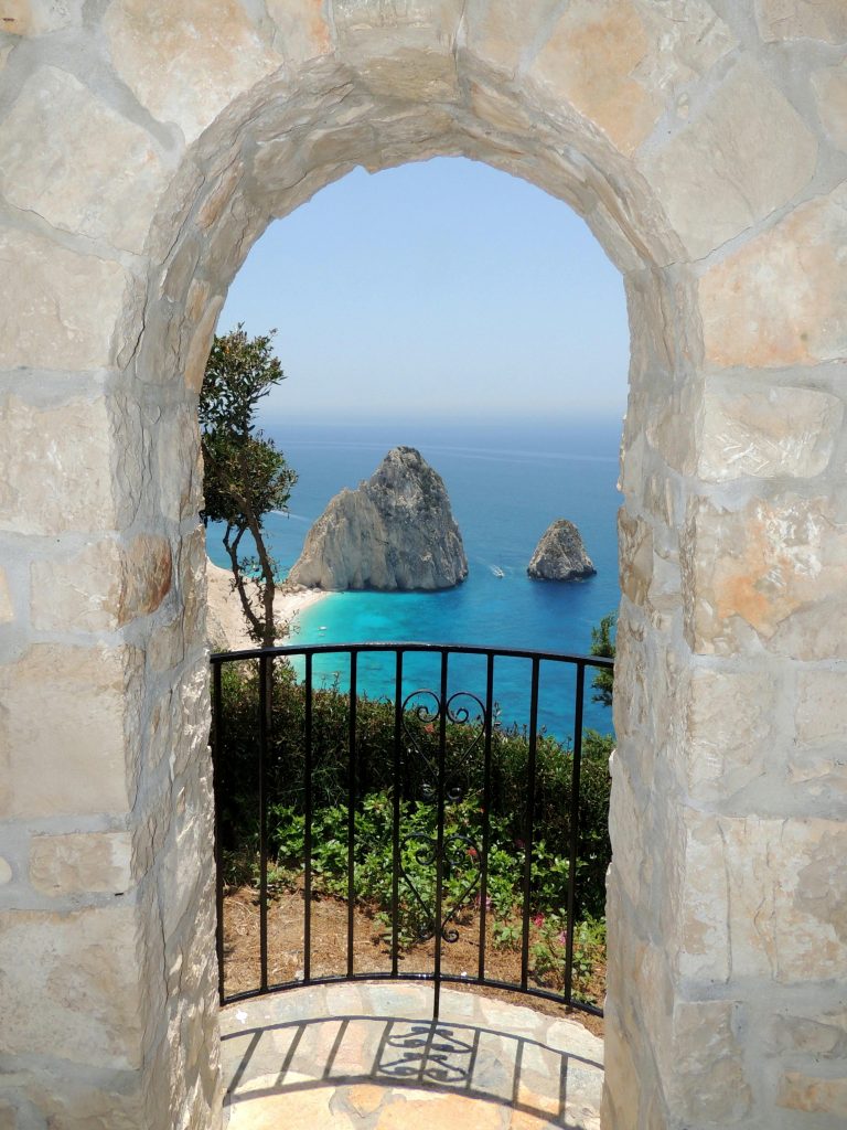 pexels-photo-12671154-12671154 View through a stone archway of stunning Greek coastline with distant rock formations.
